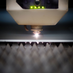 Detalle de la máquina de corte láser mientras trabaja con una plancha de aluminio anodizado.