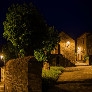 Alumbrado cálido y uniforme junto a las fachadas de piedra, reforzando la identidad rural del núcleo.