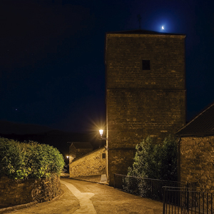 Torre de la iglesia parroquial de San Esteban iluminada con luz cálida, preservando la silueta histórica del conjunto.