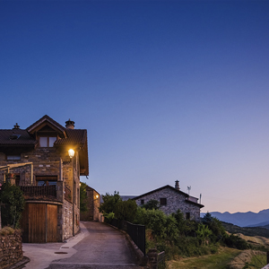 Transición del día a la noche en Sinués, con luminarias clásicas Villa XLA integradas en la arquitectura tradicional del valle de Aísa.