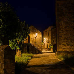 Iluminación uniforme y cálida que realza las fachadas de piedra y refuerza la identidad rural del entorno.